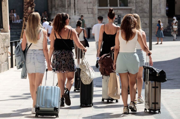 Un grupo de turista caminan con sus maletas por el centro de Valencia