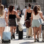 Un grupo de turista caminan con sus maletas por el centro de Valencia