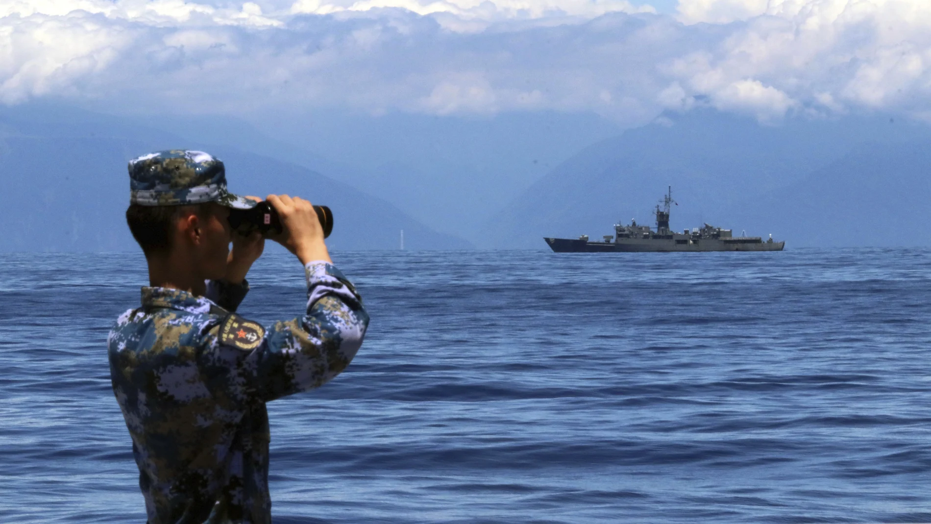 Un soldado miembro del Ejército Popular de Liberación (China) observa a través de unos prismáticos durante unos ejercicios militares mientras se ve la fragata Lan Yang de Taiwán