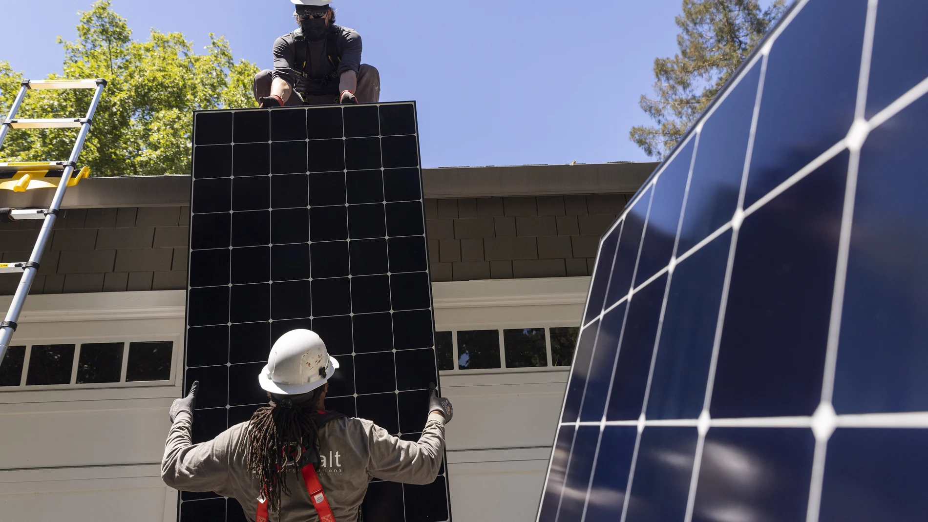 Dos trabajadores instalan paneles solares. (Jessica Christian/San Francisco Chronicle via AP)