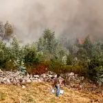 Una vecina de Meira (Pontevedra) con dos cubos de agua para sofocar las llamas