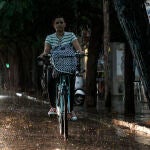 Una ciclista circula por un carril bici este jueves tarde bajo la tormenta que ha sorprendido a muchas personas