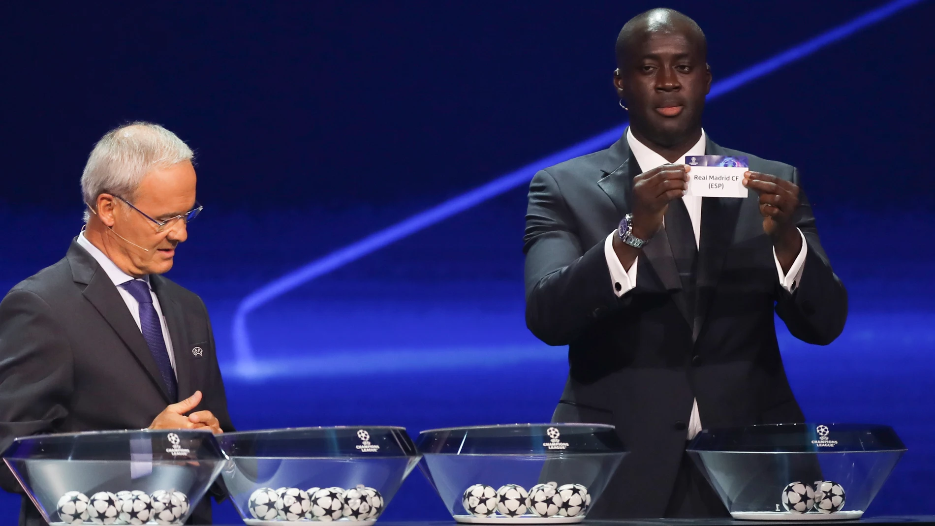 Yayá Touré muestra la papeleta del Real Madrid durante el sorteo de la fase de grupos de la Champions