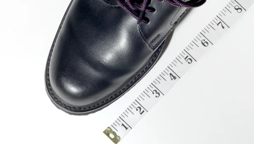 Primer plano de zapato de vestir, junto a una cinta métrica | Fuente: Dreamstime