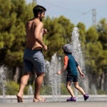 Un niño y su padre se refrescan en una fuente en Valencia