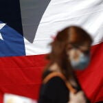 Una mujer camina frente a una bandera de Chile hoy, en Santiago (Chile).