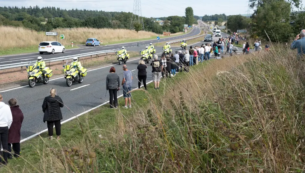 La gente se pone de pie para presentar sus respetos mientras el coche fúnebre que lleva el cuerpo de la reina Isabel II se dirige hacia Edimburgo, en la A90 en Stracathro, condado de Angus