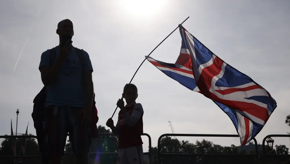 Un niño ondea la bandera británica en frente del Palacio de Buckingham