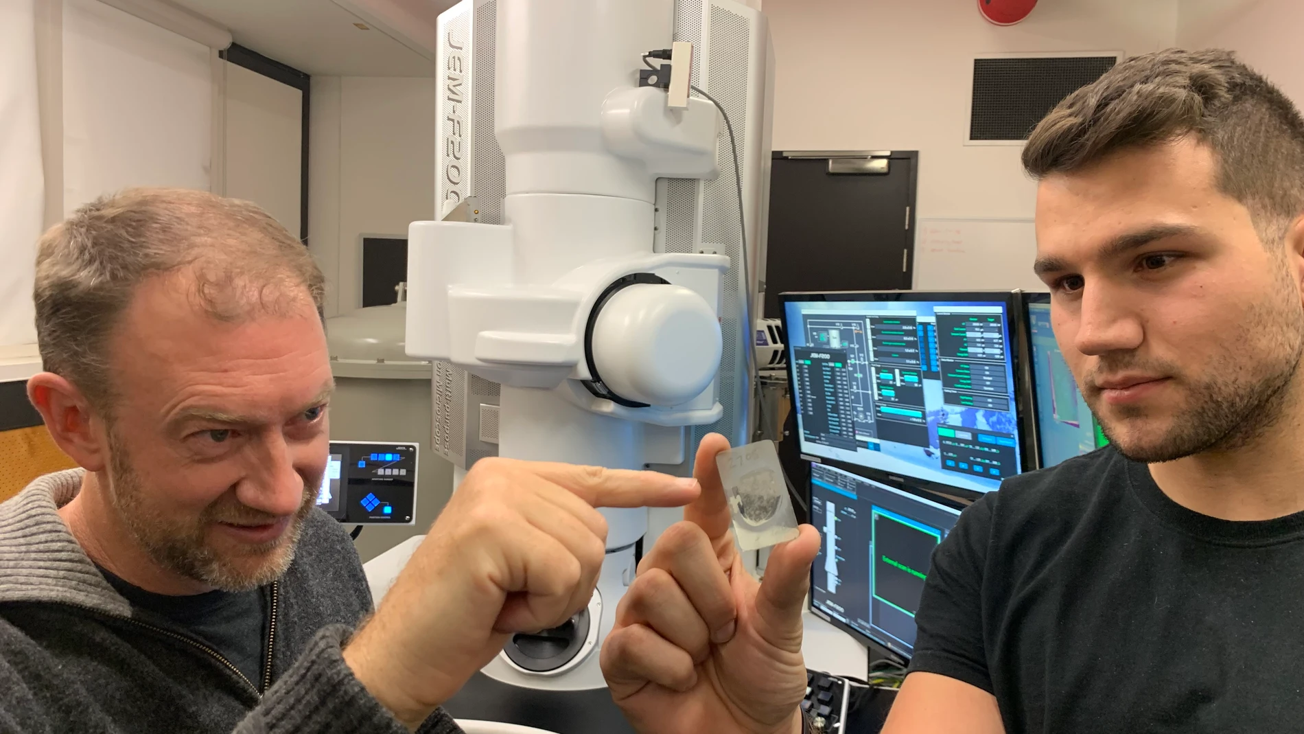 El profesor Andy Tomkins (izquierda) de la Universidad de Monash con el doctorando de la Universidad RMIT Alan Salek y una muestra del meteorito.
