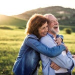Side view of senior couple hugging outside in spring nature at sunset.