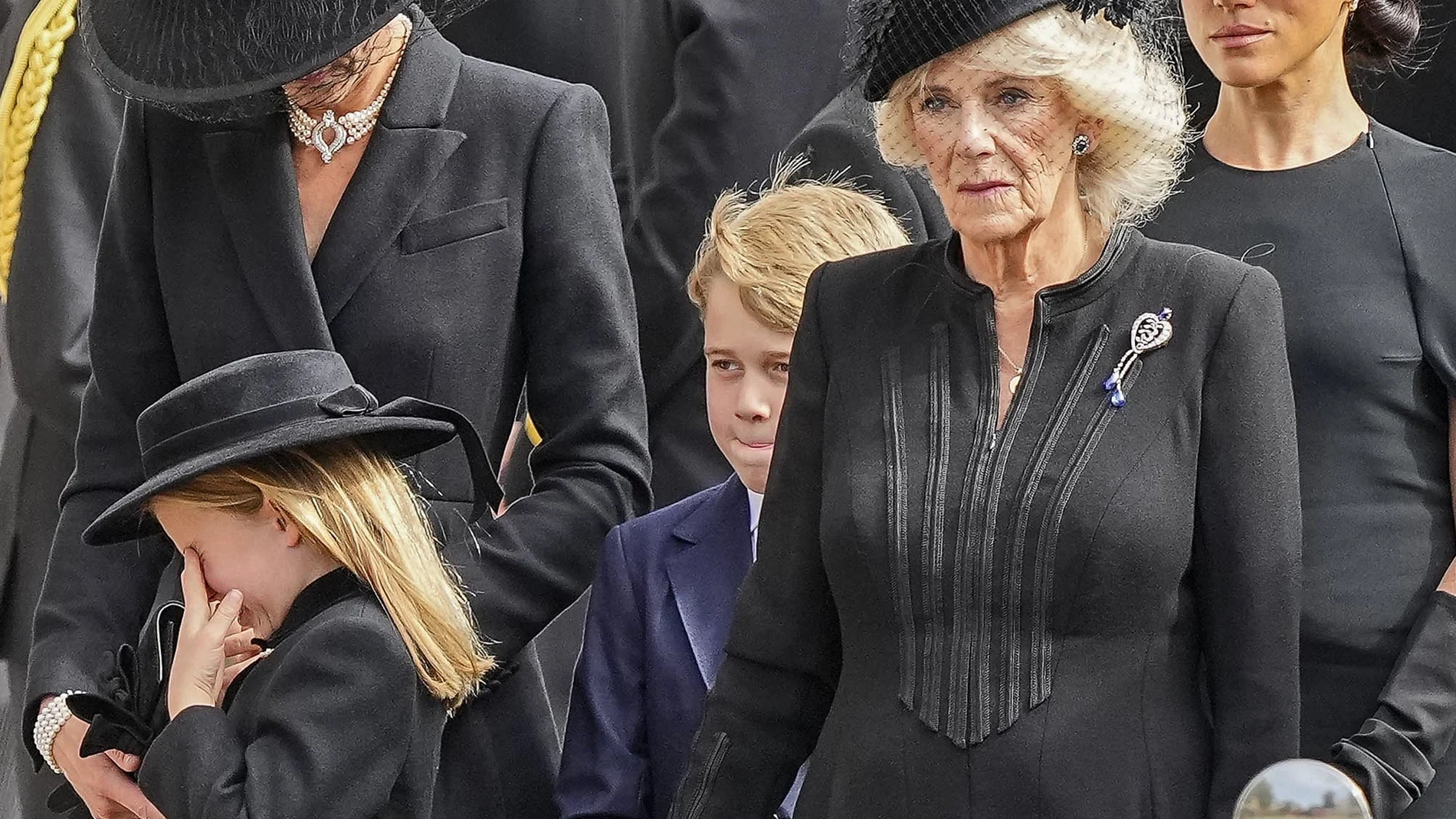 Kate, princesa de Gales, de izquierda a derecha, la princesa Carlota, limpiando su ojo, el príncipe Jorge, Camila, la reina consorte y Meghan, duquesa de Sussex, también con una lágrima