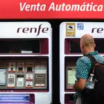Viajeros gestionan la compra de sus abonos en máquinas expendedoras de billetes en una estación de Cercanías de Madrid