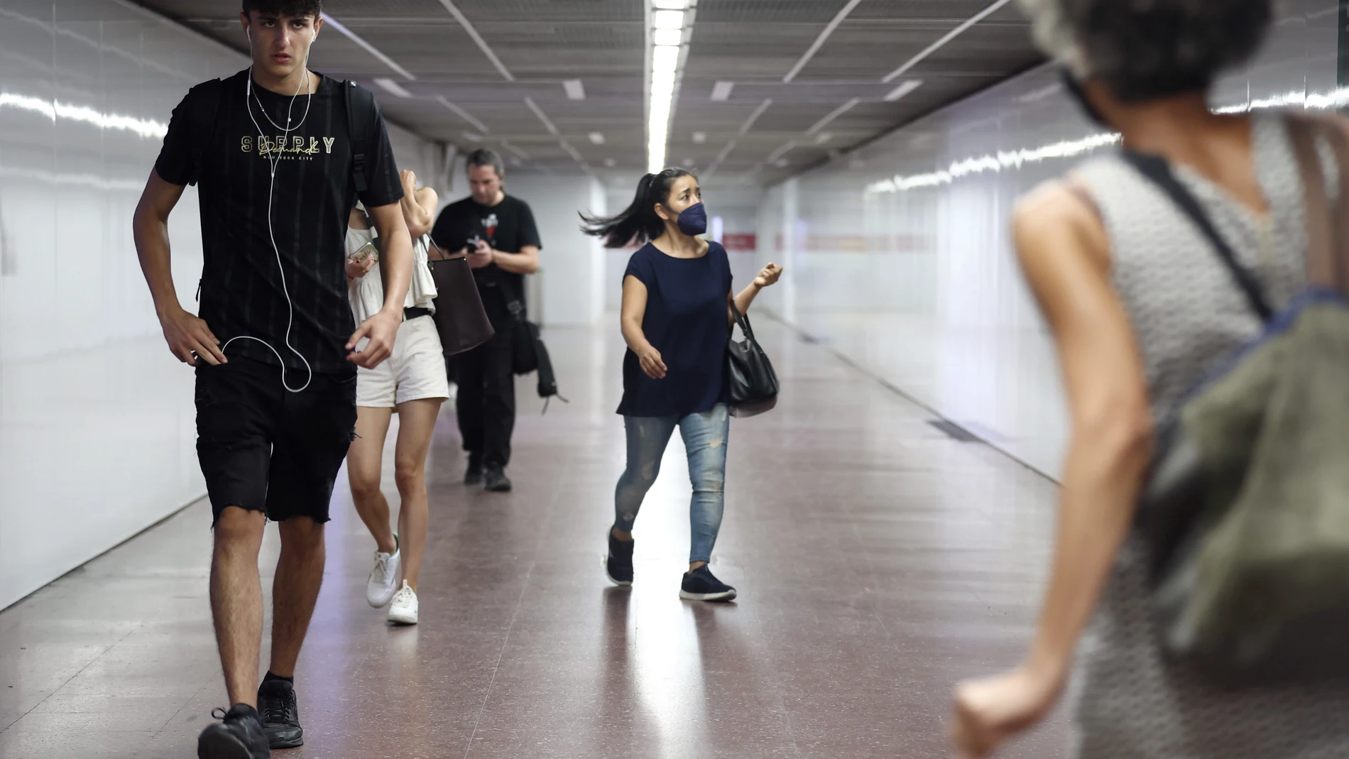 Personas con mascarilla en uno de los pasillos de la estación de tren de Chamartín (Madrid)