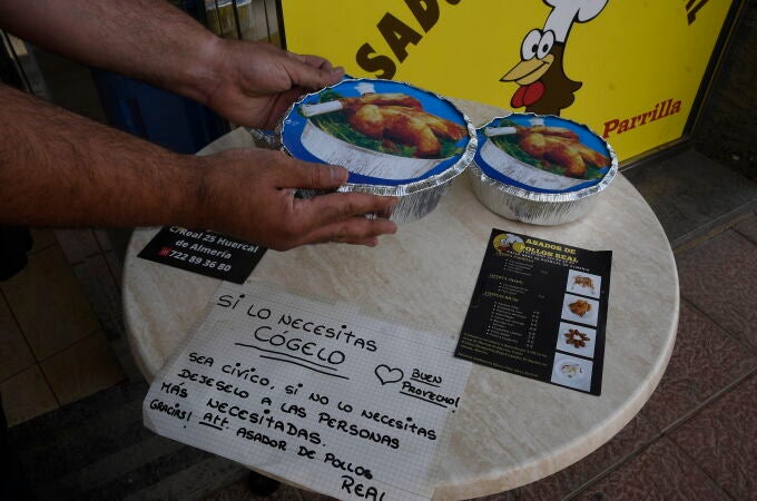 Varias pollos que el Asador Real de Huércal de Almería (Almería) coloca en una mesa donde un cartel especifica que son para se los lleven las personas necesitadas. EFE / Carlos Barba