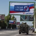 Un vehículo militar circula por una calle con un cartel que dice "Con Rusia para siempre, 27 de septiembre" antes de un referéndum en Lugansk, República Popular de Luhansk controlada por separatistas respaldados por Rusia, en el este de Ucrania, el jueves 22 de septiembre de 2022. (Foto AP)