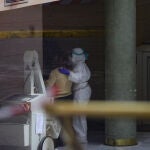 Personal sanitario ayuda a una anciana en el interior de un hotel de Sevilla adaptado como hospital