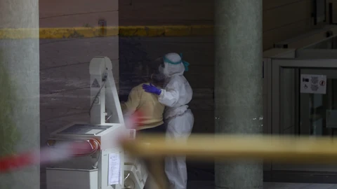 Personal sanitario ayuda a una anciana en el interior de un hotel de Sevilla adaptado como hospital