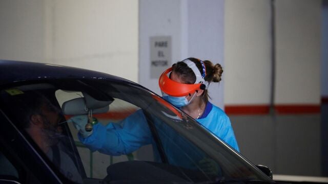Una sanitaria realiza una prueba PCR a un hombre a través de la ventanilla de un vehículo