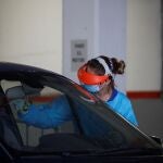 Una sanitaria realiza una prueba PCR a un hombre a través de la ventanilla de un vehículo
