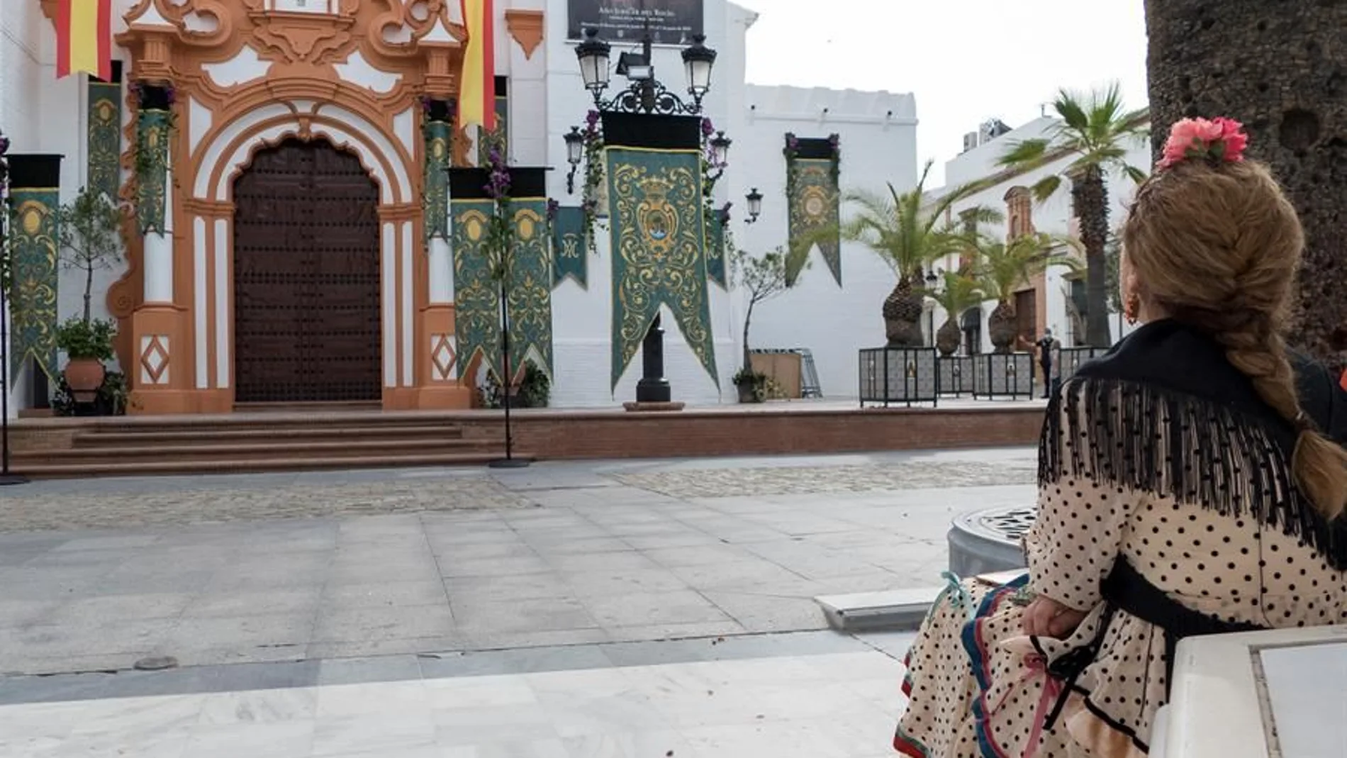 Una mujer vestida de sevillana, ayer frente a la parroquia de Nuestra Señor de la Asunción en El Rocío