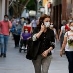 Varias personas caminan por la calle con mascarillas puestas en Sevilla