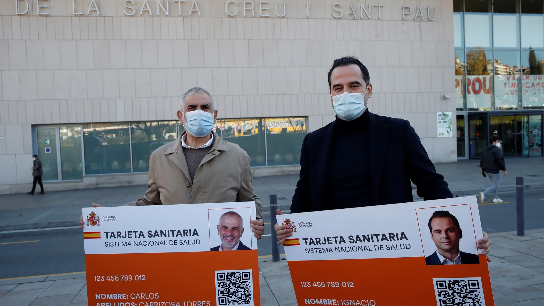 El presidente del grupo de Ciudadanos en el Parlament, Carlos Carrizosa (i) y el vicepresidente de la Comunidad de Madrid, Ignacio Aguado (d) con una representación de la tarjeta sanitaria tras la rueda de prensa frente al Hospital de Sant Pau en Barcelona este sábado