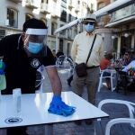 Un camarero desinfecta una mesa en un bar en el centro de Málaga