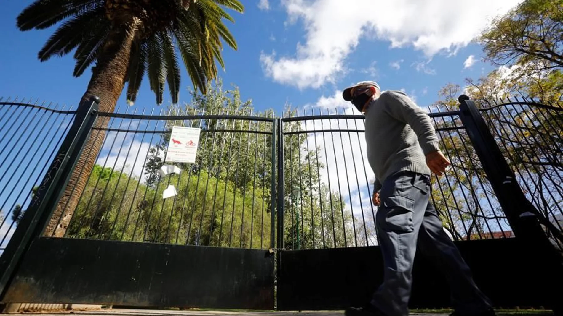 Un hombre pasa junto a las cancelas de un parque cerradas por la Covid-19 en Córdoba