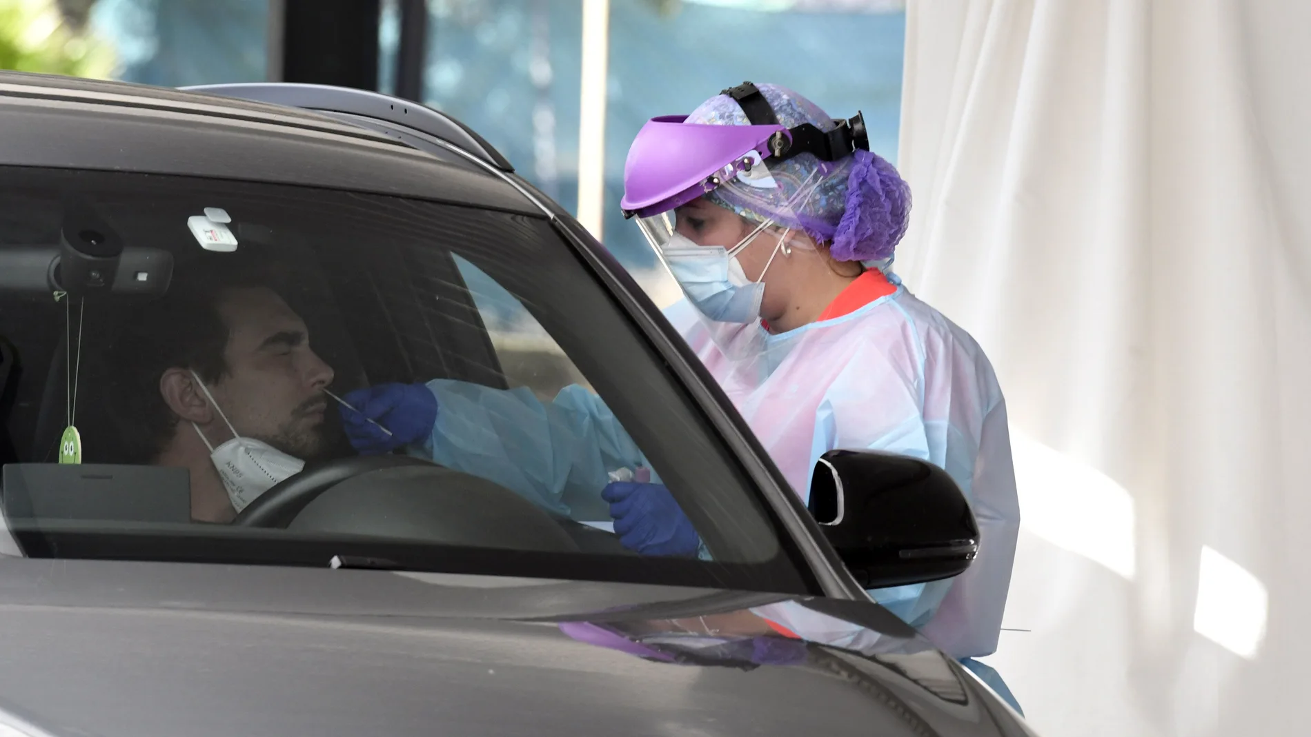 Una sanitaria realiza una prueba de detección de la covid a un hombre en su vehículo