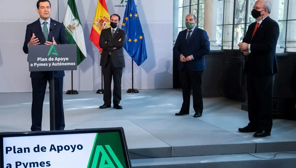 El presidente de la Junta de Andalucía, Juanma Moreno, durante su intervención, en presencia de Javier González de Lara, el segundo por la izquierda, Lorenzo Amor y Javier Sánchez Rojas, a la derecha