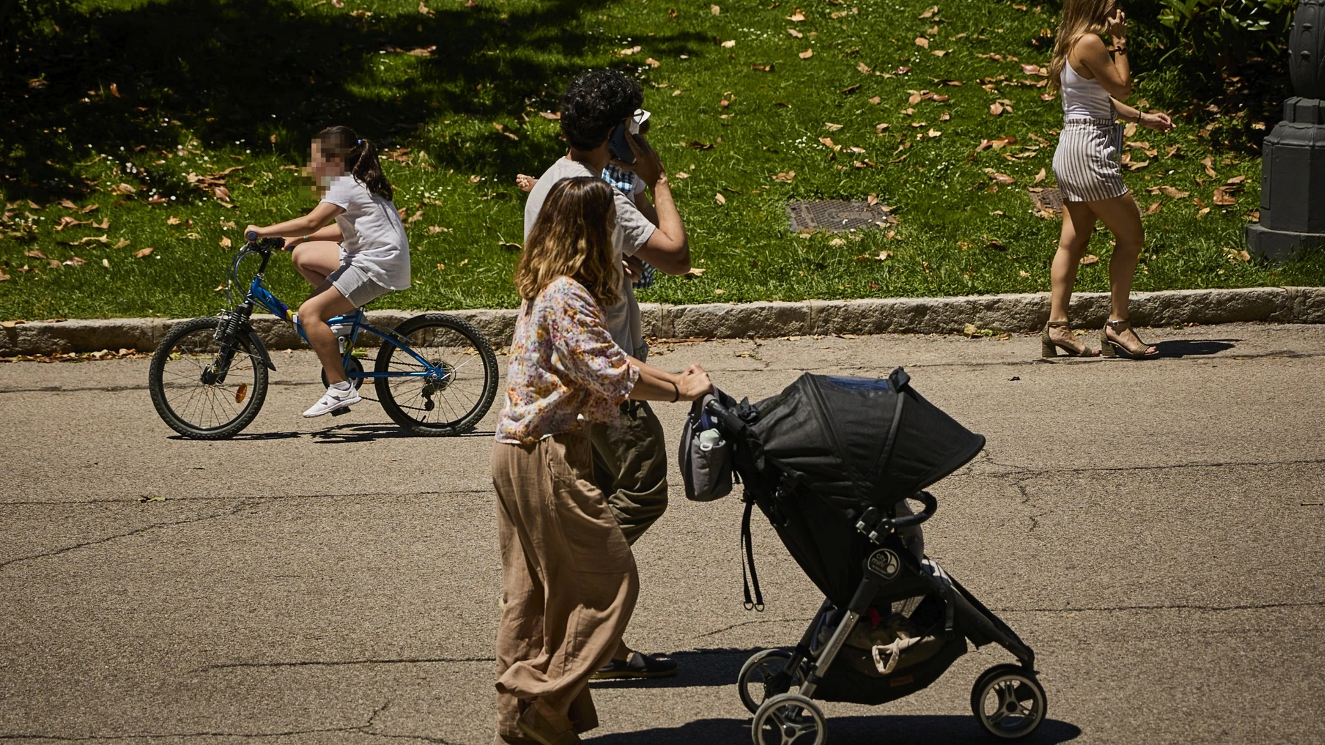 Familias con sus carritos de bebe pasean por el Retiro madrileño