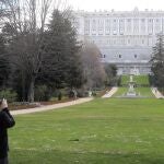 Una persona toma una fotografía de los jardines del Campo del Moro en Madrid, con el Palacio Real al fondo