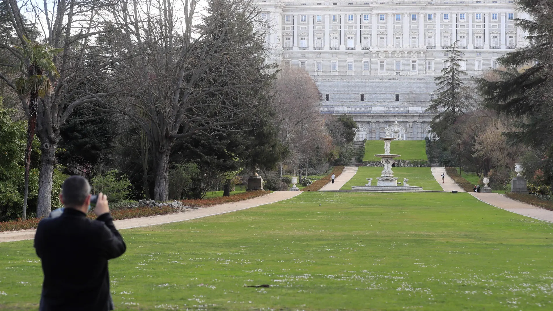 Una persona toma una fotografía de los jardines del Campo del Moro en Madrid, con el Palacio Real al fondo