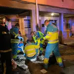 Sanitarios del Summa-112 y efectivos de los Bomberos de la Comunidad de Madrid atienden a una mujer herida en un incendio en El Caserío, en Getafe