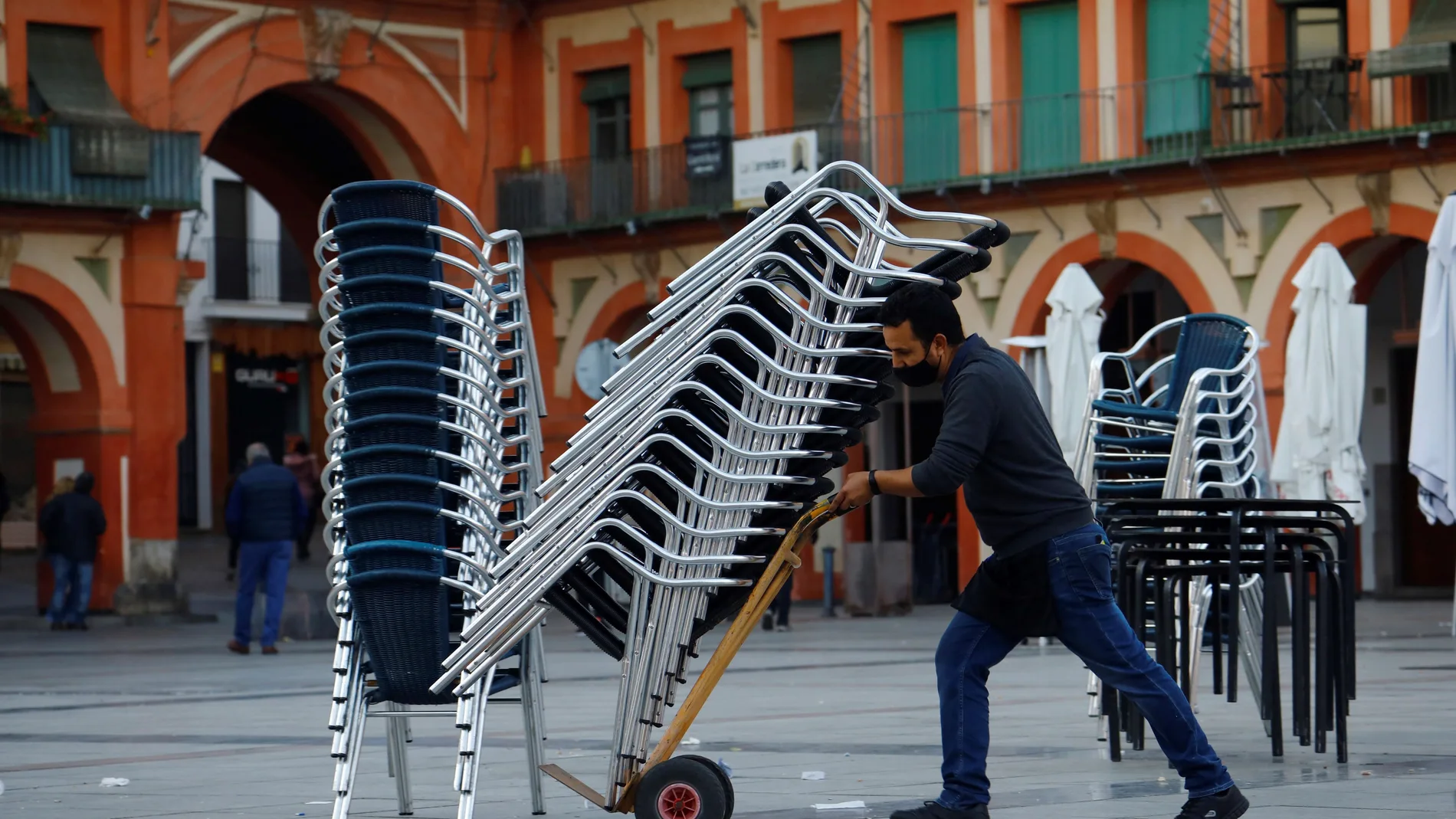 Un trabajador de la hostelería recoge la terraza de un bar en Córdoba