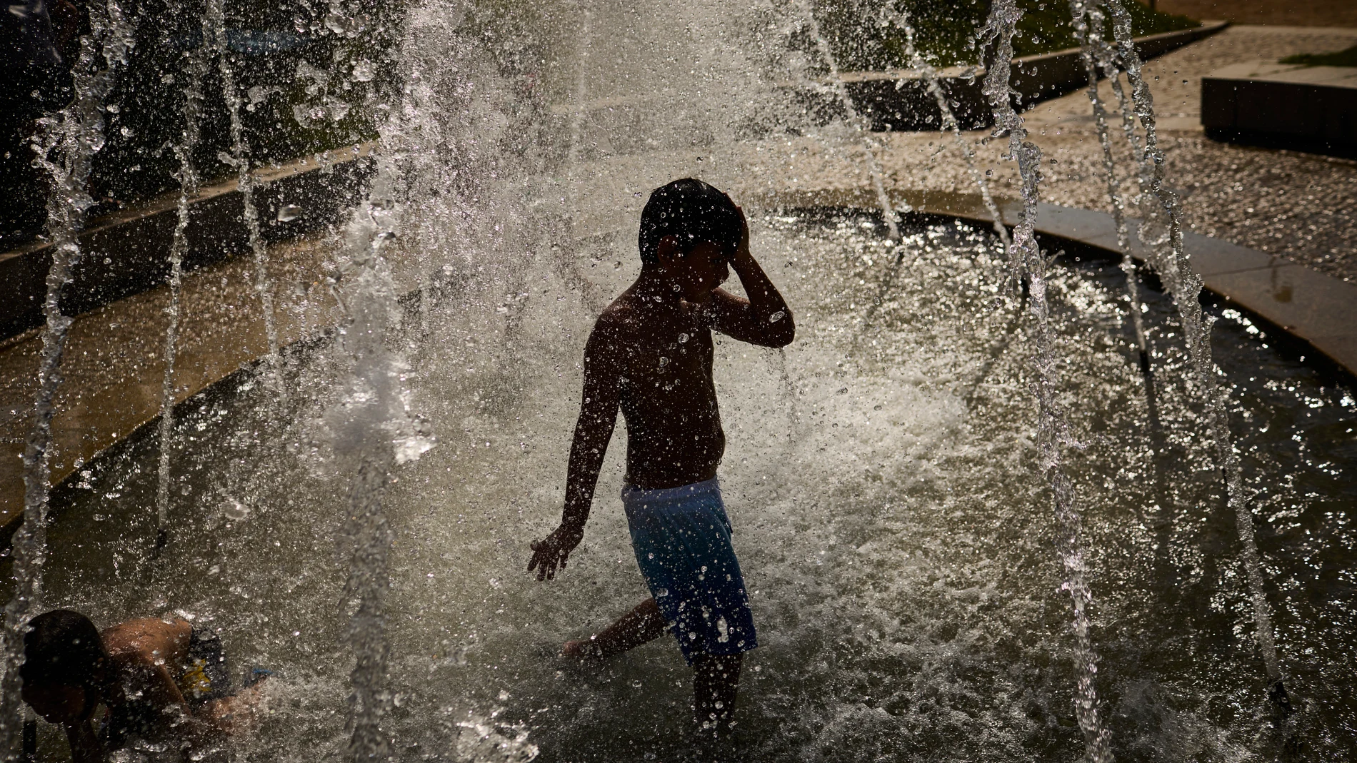 Unos niños juegan en una fuente en Madrid Rio