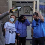 Una pareja de agraciados celebran su suerte, junto a las loteras en la administración de lotería que ha repartido parte del "Gordo" en Punta Umbría