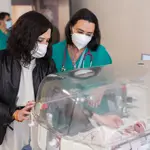 La presidenta de la Comunidad de Madrid, Isabel Díaz Ayuso, observa a un bebé durante su visita al Complejo Hospitalario 12 de Octubre