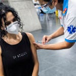 Un sanitario administra una dosis de la vacuna de Pfizer a una mujer en el Wizink Center