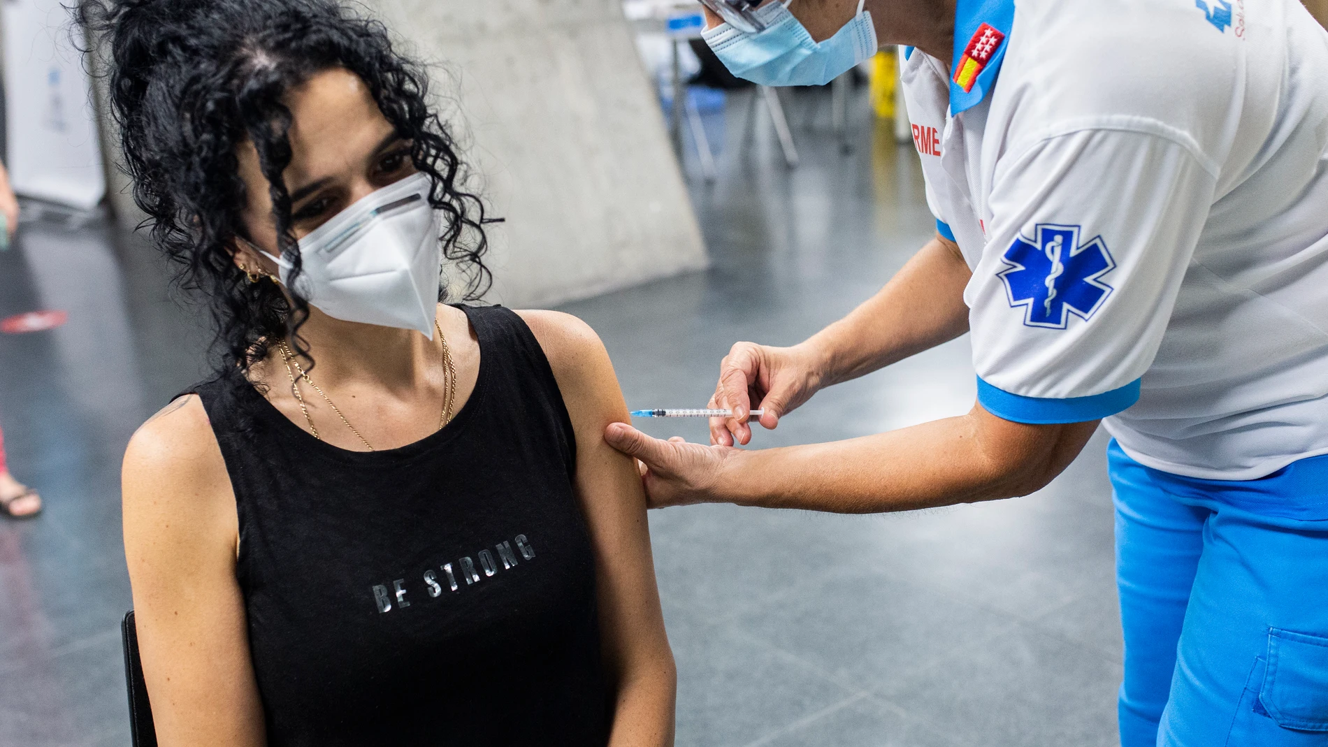 Un sanitario administra una dosis de la vacuna de Pfizer a una mujer en el Wizink Center
