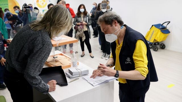 Un empleado de Correos conversa con la presidenta de una mesa electoral en el colegio La Inmaculada-Marillac en Madrid durante la jornada electoral