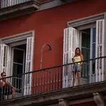 Turistas toman el sol en el balcón de su hotel en la Plaza Mayor