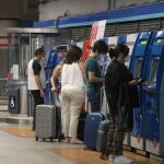 Varias personas recargan sus abonos de metro en la estación de Metro de Atocha, en Madrid