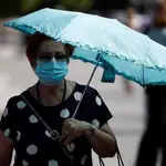 Una mujer pasea por el centro de la capital protegida con una sombrilla