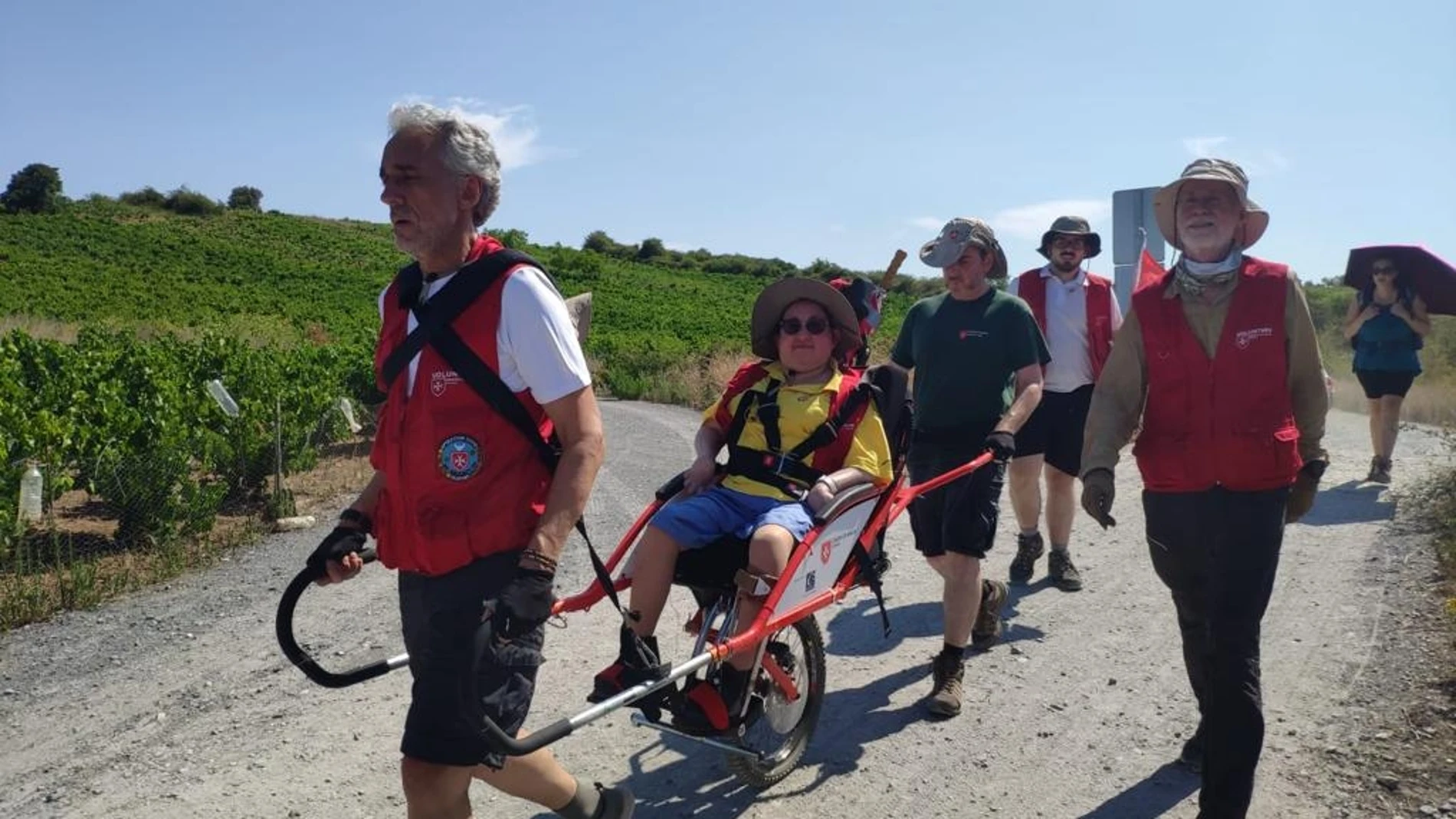 Imagen de como llevan los voluntarios a los peregrinos con silla de ruedas a recorrer el Camino de Santiago