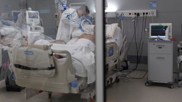 Un sanitario junto a un paciente en el hospital Isabel Zendal de Madrid