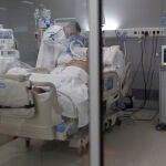 Un sanitario junto a un paciente en el hospital Isabel Zendal de Madrid
