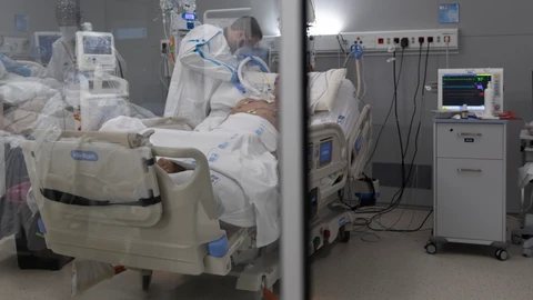 Un sanitario junto a un paciente en el hospital Isabel Zendal de Madrid