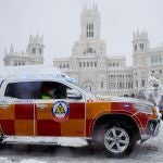 Un vehículo del Samur circula sobre la nieve por la plaza Cibeles de Madrid, este sábado.