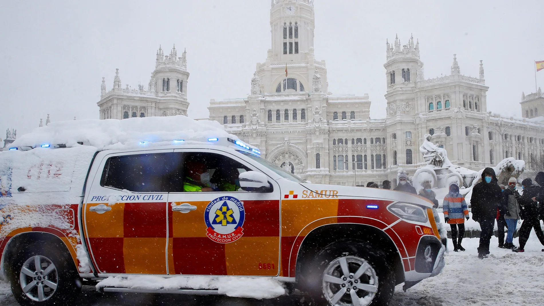 Un vehículo del Samur circula sobre la nieve por la plaza Cibeles de Madrid, este sábado.